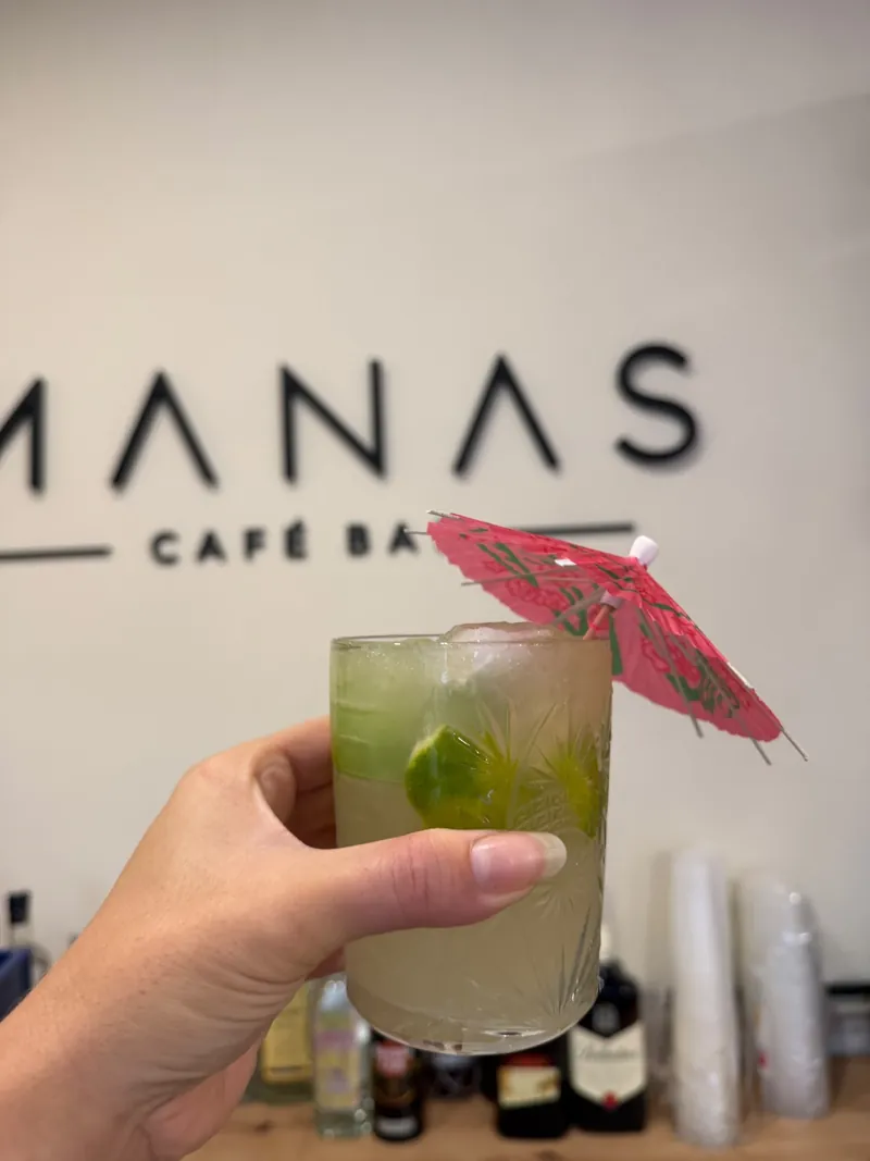 Caipirinha con sombrillita frente al logo de Manas